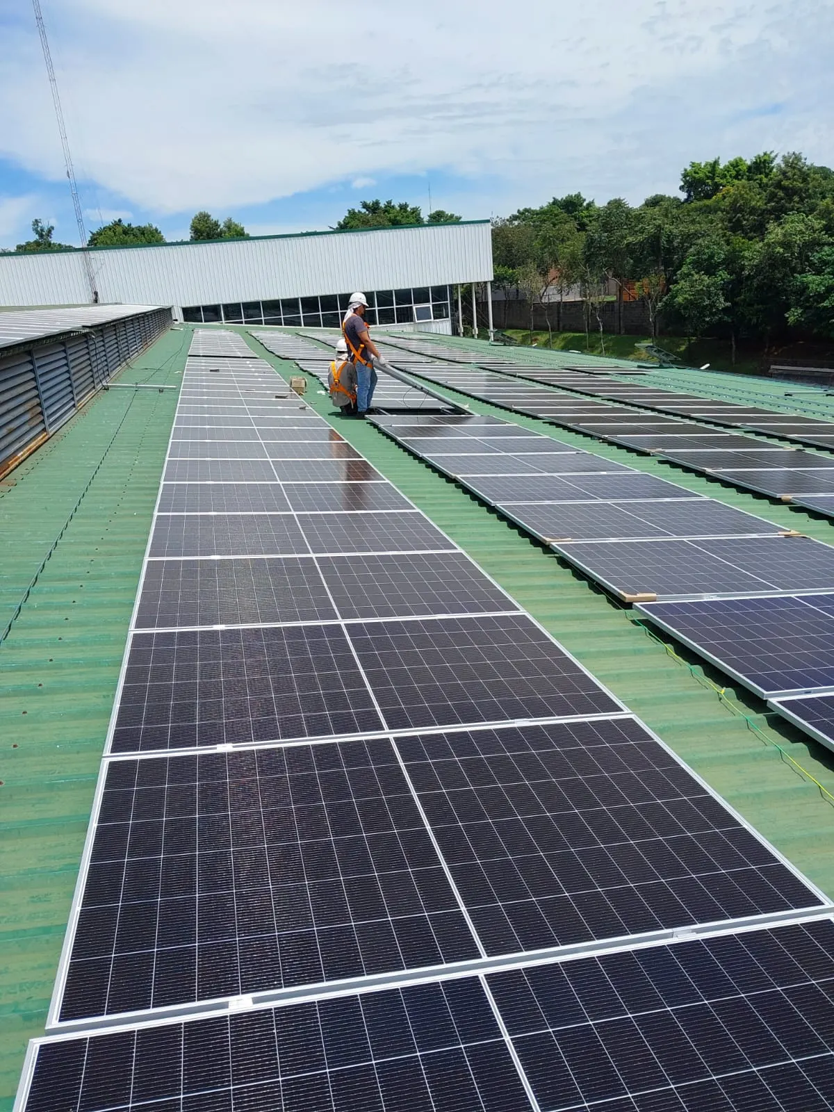Dos instaladores montando paneles solares sobre el techo de una nave